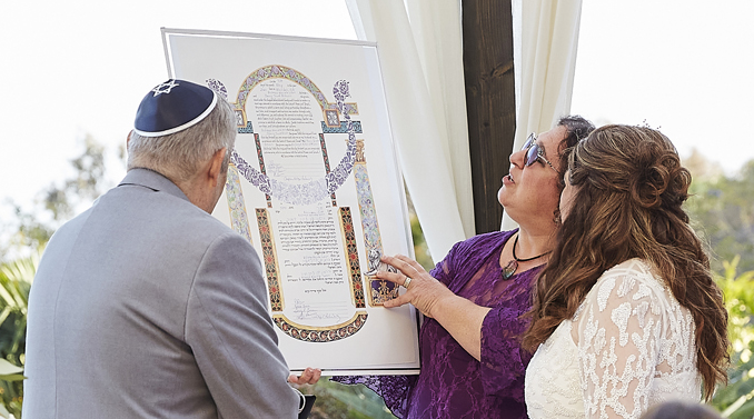 Couple looks at ketubah (Jewish ceremonial marriage document). Mitzi Schwarz - Wedding Officiant